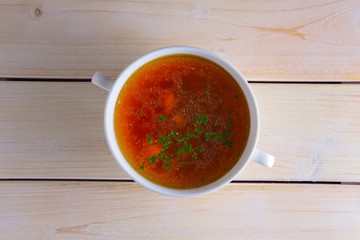 Rich beef broth in small soup bowl Served with fresh dill  on wooden table