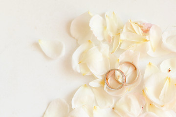 Beautiful toned picture with wedding rings lie on white against the background of flowers