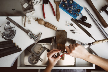 Creative chaos. Top view of jeweler's workbench with different tools for making jewelry. Female...