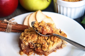 Apple crumble on with dish with spoon and fresh green and red apple with cinnamon stick on wooden floor. Easy and Basic dessert menu.