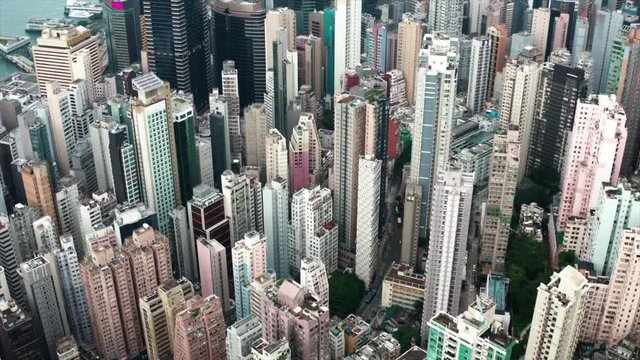 Drone shot following streets of Hong Kong modern skyscraper high-rises.