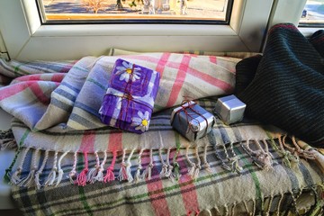 Autumn still life - Warm knitted scarf and small gifts near a window
