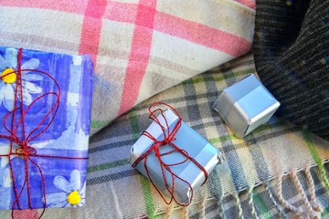 Holidays, winter, celebration and still life concept -  gift boxes, warm scarf  and plaid at home. Romantic still life. Close-up