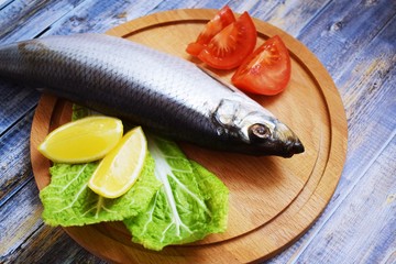 Delicious herring with lemon and tomatoes on lettuce leaves.