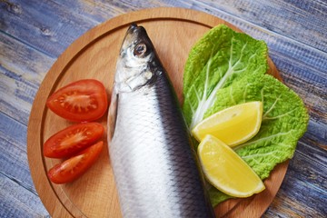 Delicious herring with lemon and tomatoes on lettuce leaves.