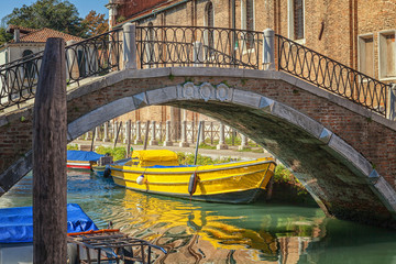 Yellow boat at the stone bridge, Venice, Italy