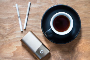 Fototapeta na wymiar Coffee in a black cup and tobacco heating system