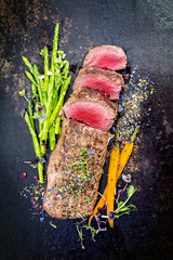Traditional barbecue aged venison backstrap roast with green asparagus, carrots and herbs as top...