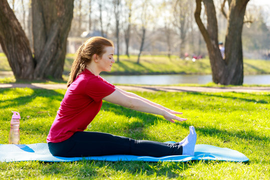 Smiling girl in the park exercise on the yoga mat