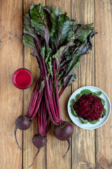 Bunch of fresh organic beetroot on wooden background with beet juice and salad