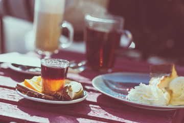 Outdoor cafe. Wooden vintage table and coffee, tea and cake on it. Shallow depth of field and a matte filter in an intagram style.
