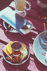Outdoor cafe. Wooden vintage table and coffee, tea and cake on it. Shallow depth of field and a matte filter in an intagram style.