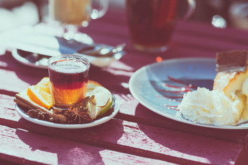 Outdoor cafe. Wooden vintage table and coffee, tea and cake on it. Shallow depth of field and a matte filter in an intagram style.