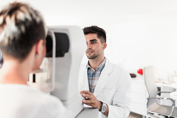 Fototapeta na wymiar Male optometrist checking patient's vision at eye clinic. Medical examination.