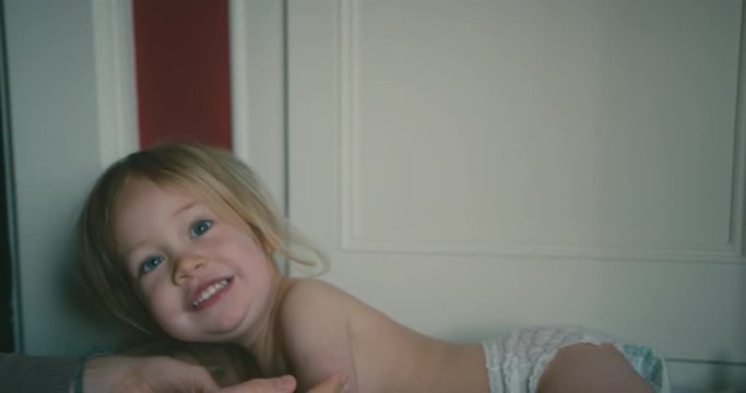 Mother applying lotion to the skin of little toddler in his diaper