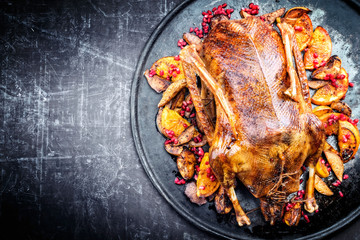 Traditional roasted stuffed Christmas goose with orange and pomegranate as top view on a board with copy space left