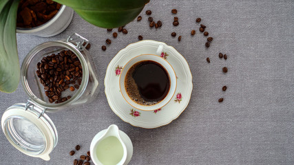 Kawa świeżo przygotowana w starej filiżance w otoczeniu ziarenek kawy i kwiatka