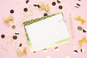 Blank sheet of paper, notebook on a festive pink background with golden confetti and glitter....