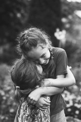 Black and white portrait of Two Happy little girls laughing and hugging at the  summer park.