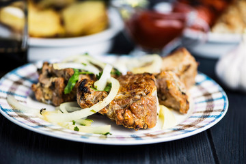 Pork meat barbecue with marinated onions on a wooden background