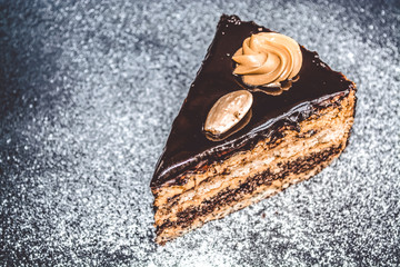 Chocolate home-made tasty cake on a gray monophonic background with sugar powder. Fresh pastries. Piece. Pie. Food.