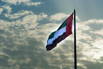 UAE National Flag waving in air with clouds background during sunset at winter