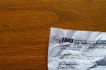 Paper tax form, crumpled up on a wooden table