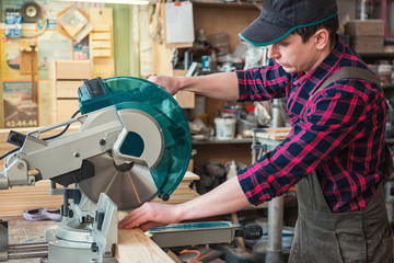 Construction worker cutting wooden board with circular saw