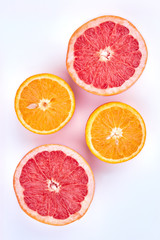 Sliced grapefruit and orange, top view. Ripe grapefruit and orange cut in halves on light background. Ingredients for healthy beverage.