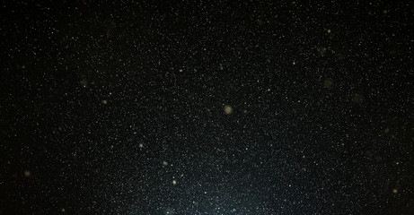 Snow flies in the sky at night as a background