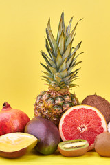 Summer composition from exotic fruits. Delicious tropical fruits including pineapple, pomegranate, mango, coconut, grapefruit and kiwi fruit on color background.