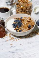 bowl of healthy wholegrain flakes, yogurt and fresh blueberries on white table, vertical