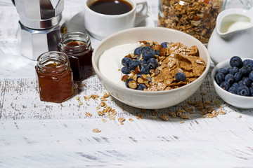 bowl of healthy wholegrain flakes, yogurt and fresh blueberries on white table