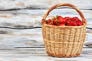 Fototapeta na wymiar Strawberries in basket and copy space. Ripe sweet strawberries in wicker basket on wooden boards.