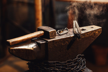 closeup of a blacksmith anvil with a hammer, tongs and firesteel.