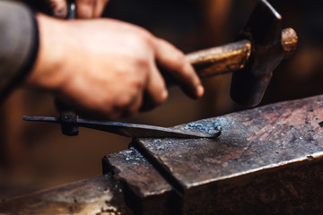 blacksmith makes an artistic forging of hot metal on the anvil.