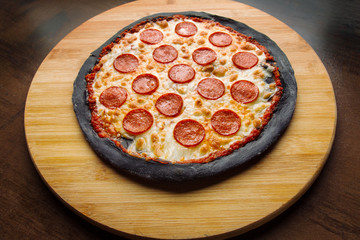 Pepperoni pizza on black pastry, beautiful light.