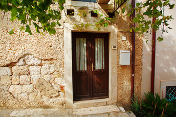 Fototapeta na wymiar Charming small home with brown front door and summer garden containers filled with annual flowers.
