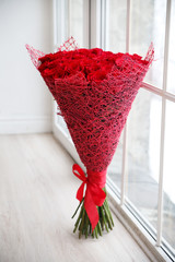 A large bouquet of red roses near the window.