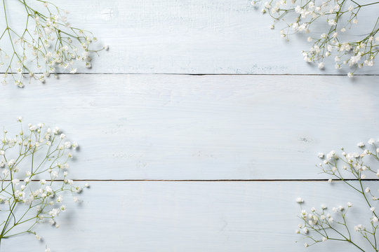 Spring background, flowers frame on blue wooden table. Banner mockup for Womans or Mothers Day, Easter, spring holidays. Flat lay, above view.