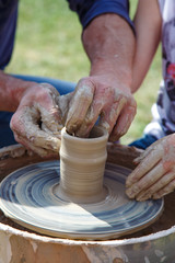 Hands of master  and apprentice on potter's wheel