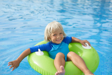 Happy little boy with  life ring has fun in the swimming pool