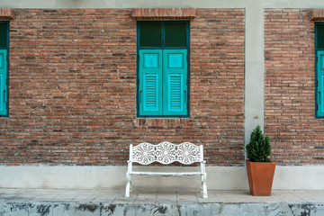 Fototapeta na wymiar White bench with brick wall with blue window, vintage style