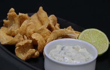 deep fried anchovies with tartar sauce and lime wedge in a serving dish