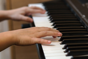 Fototapeta na wymiar Hands of the child on the piano keys. Selective focus.