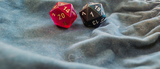 Two polyhedral d20 game dice exhibiting a 20 and a 1