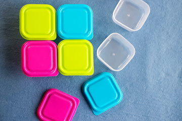 Square plastic containers with bright multi-colored lids.