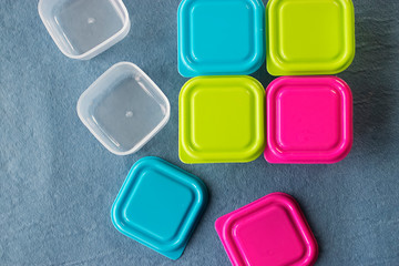 Square plastic containers with bright multi-colored lids.