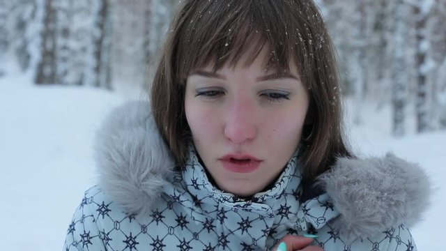A young woman coughing in a winter park. You need to apply pills. The trees are covered with snow.