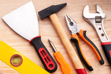 Level, spatula, screwdriver, hammer, pliers, adjustable wrench. Set of construction tools on a concrete background.